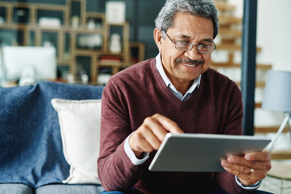 older-latin-man-sitting-on-couch-using-tablet-computer_istock-1135956740.jpg